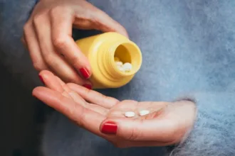 PersonTippingTabletsFromMedicationBottle