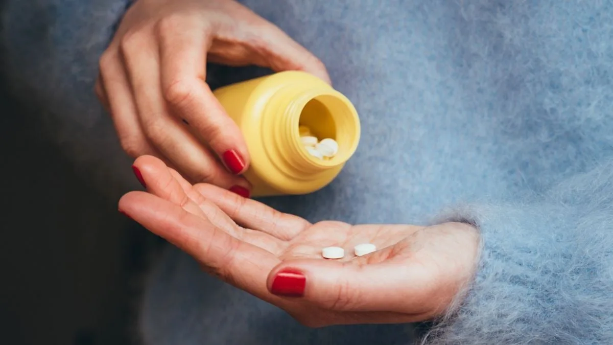 PersonTippingTabletsFromMedicationBottle